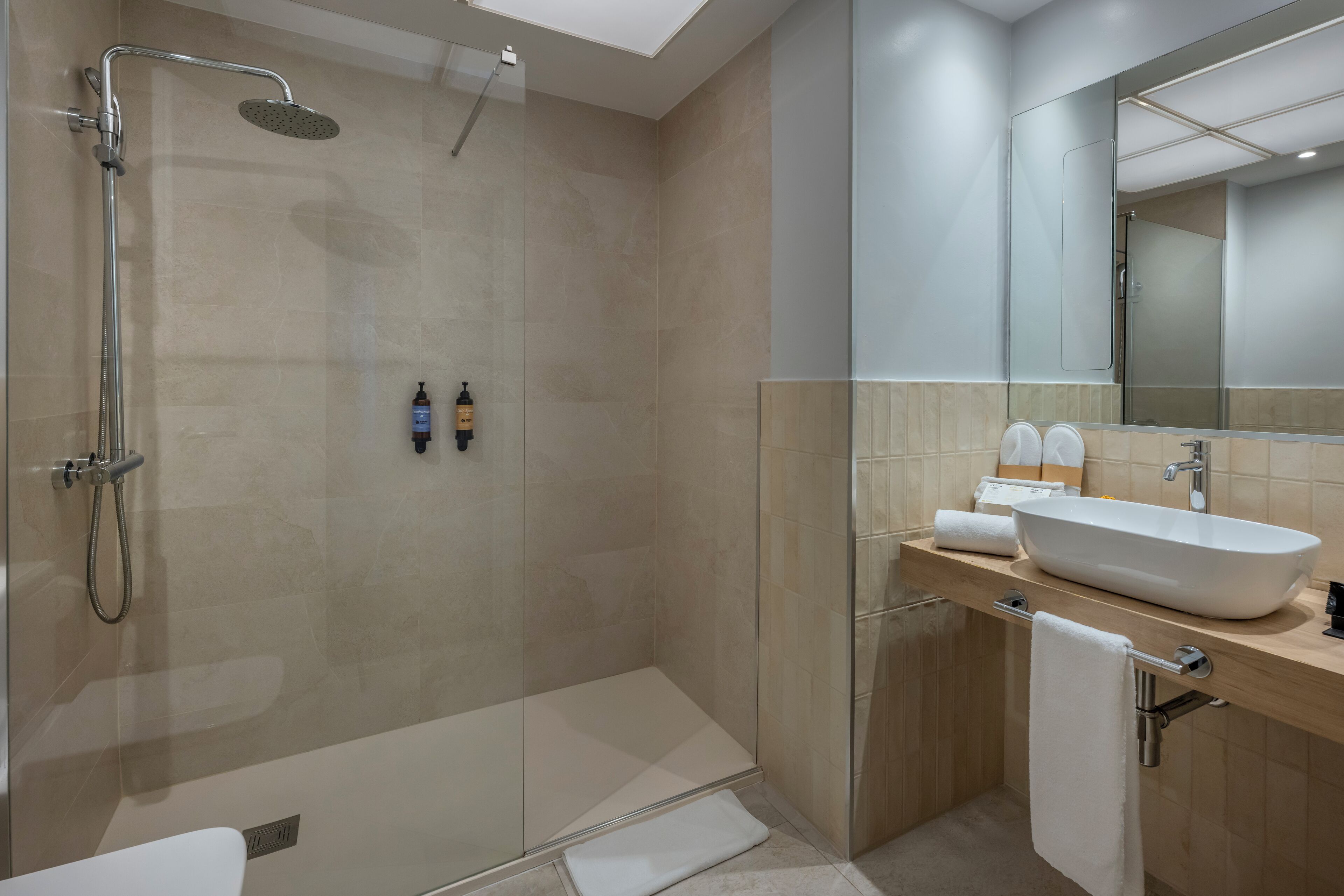 Un baño moderno con ducha envuelta en vidrio, un lavabo espacioso y un espejo sobre el mostrador.