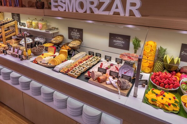 Una exhibición de alimentos con diversos quesos, frutas y pasteles.