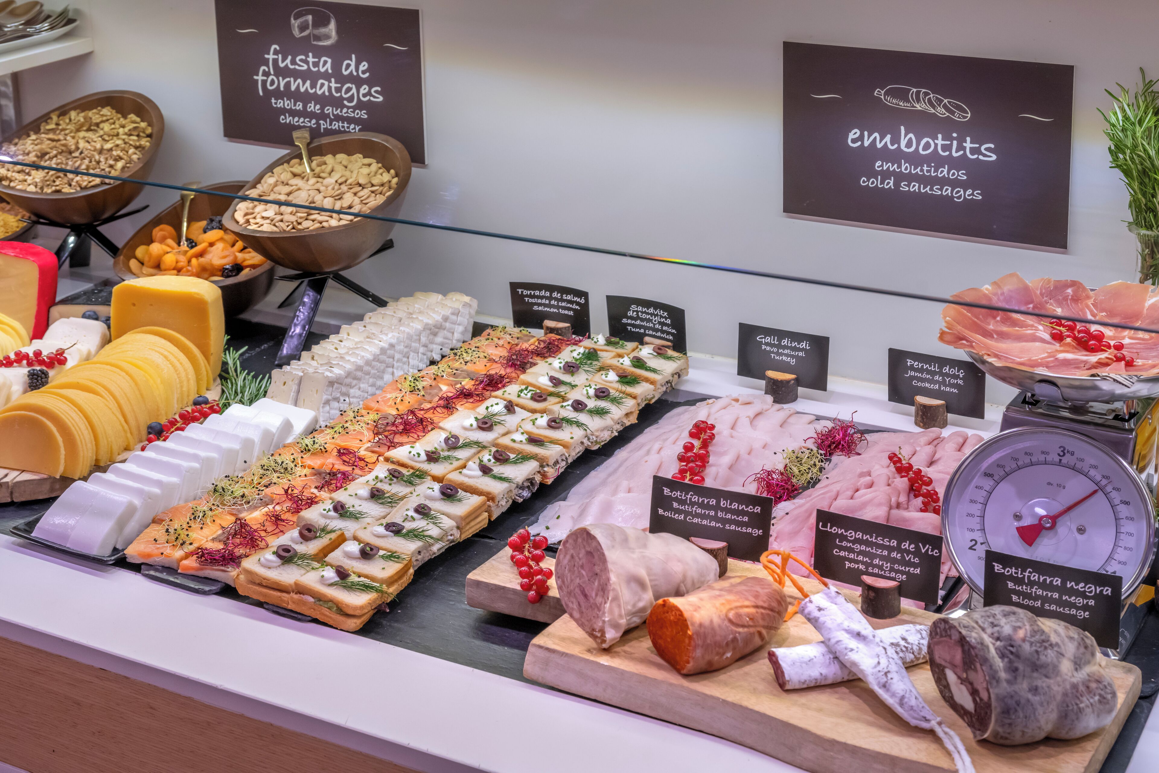 A deli counter with various cheeses, cold cuts, and cured meats.