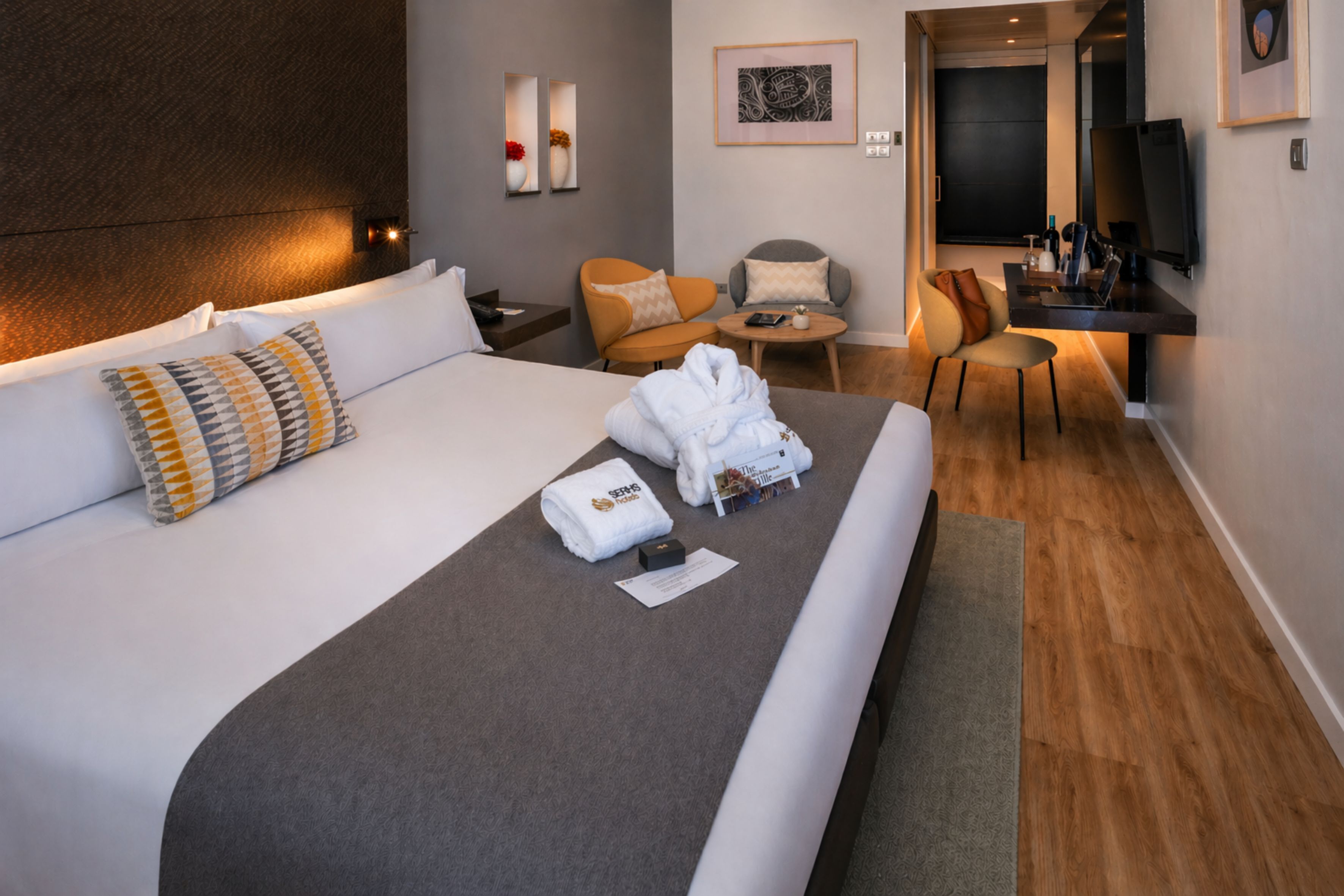 A hotel room with a large bed, a desk, a chair, and a TV.