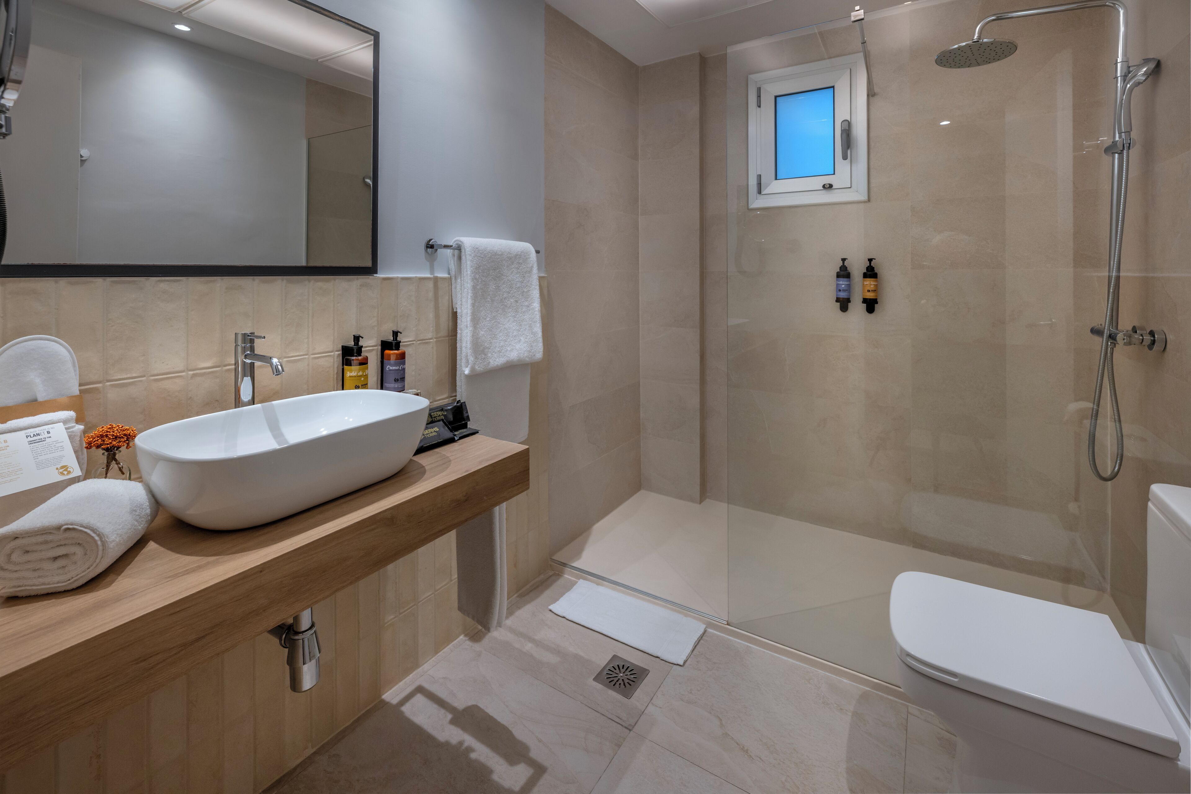 Un bany modern amb un lavabo gran, un armari de dutxa de vidre i un vàter.
