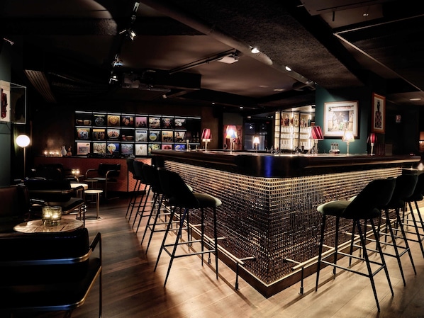 Zona de bar con mostrador, taburetes y una pared que exhibe diversos objetos.