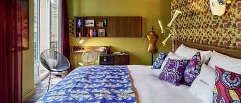A room with a bed, a desk, a chair, and a wall with a decorative headboard.