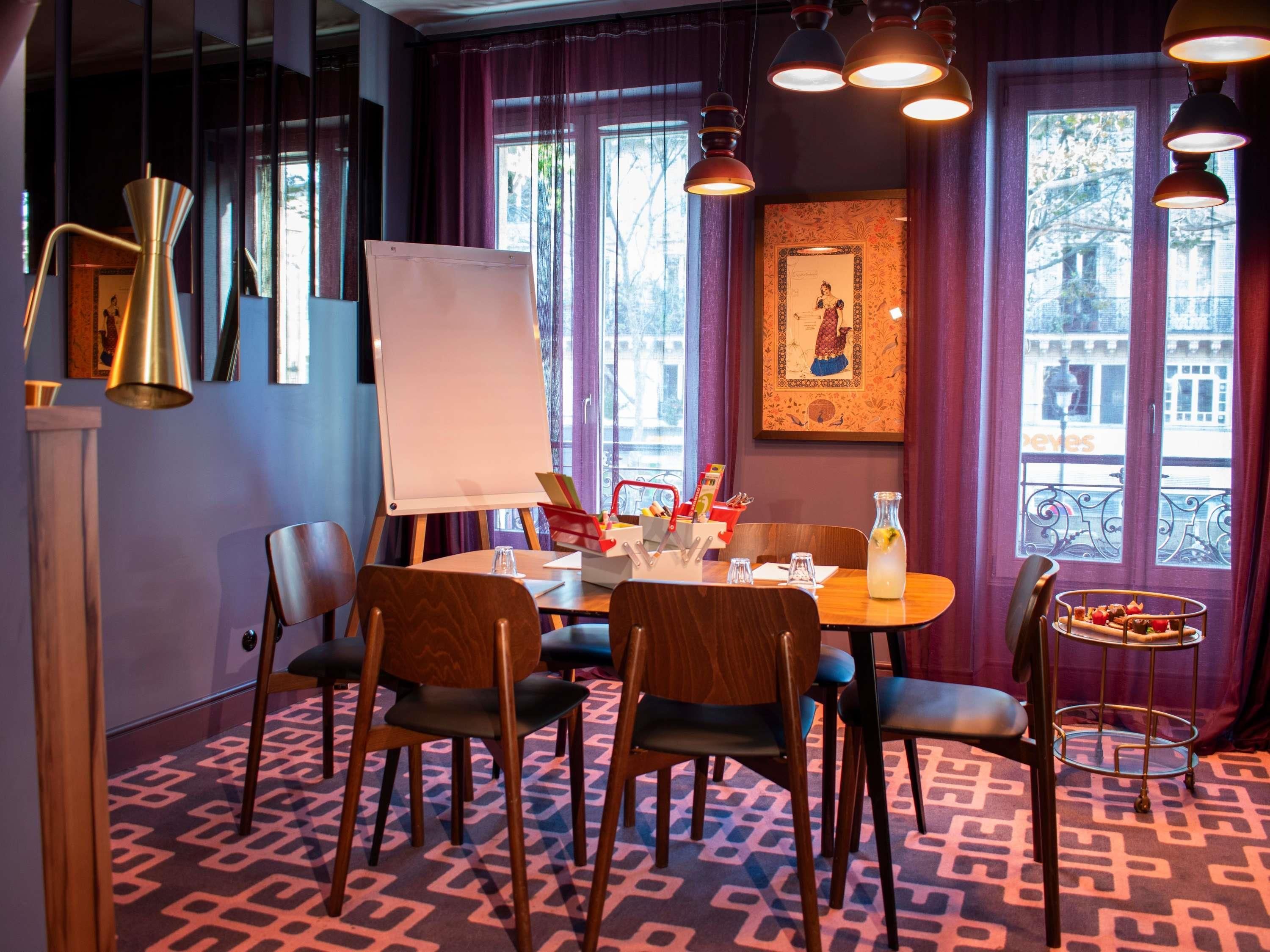 Una sala de conferencias con una pizarra, una mesa, sillas y una lámpara decorativa.