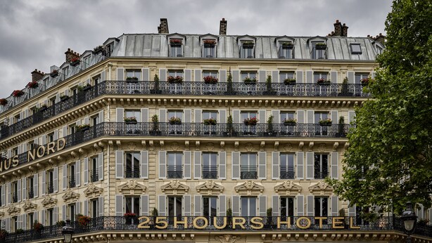Un hôtel à plusieurs étages doté de balcons, d’une enseigne bien visible indiquant « 25 Hours Hotel », et d’un style architectural européen classique.