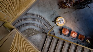Un escalier menant à un espace détente avec une table et des chaises, un vélo et un tapis à motifs.