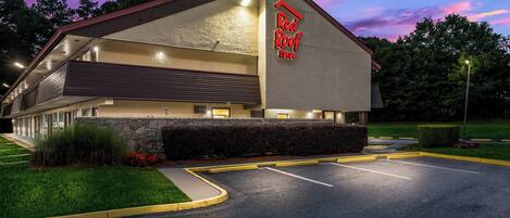 A Red Roof Inn building with a stone facade, a flat roof, and a parking lot.
