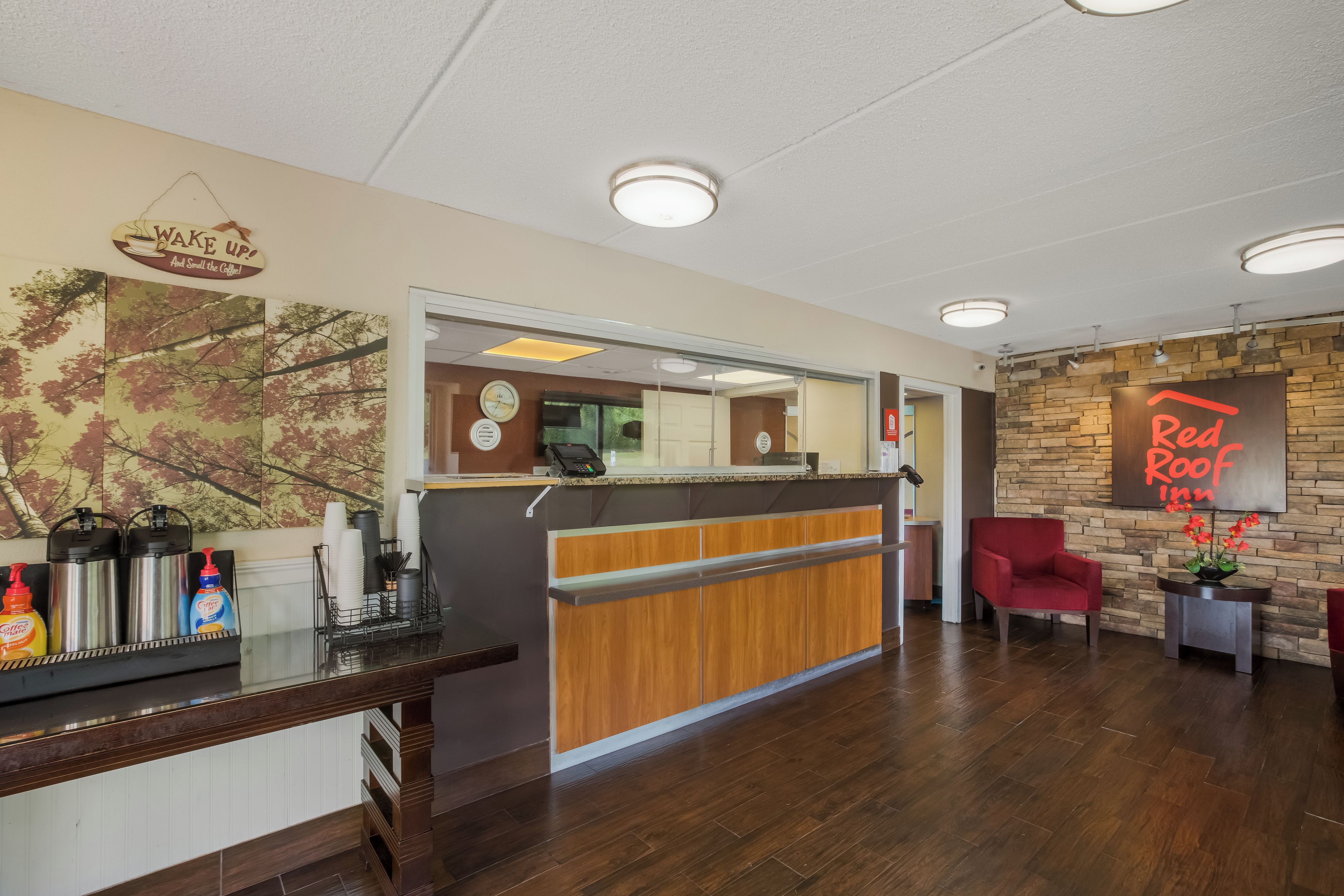 A reception area with a wooden counter, a clock, and a Red Roof Inn sign.