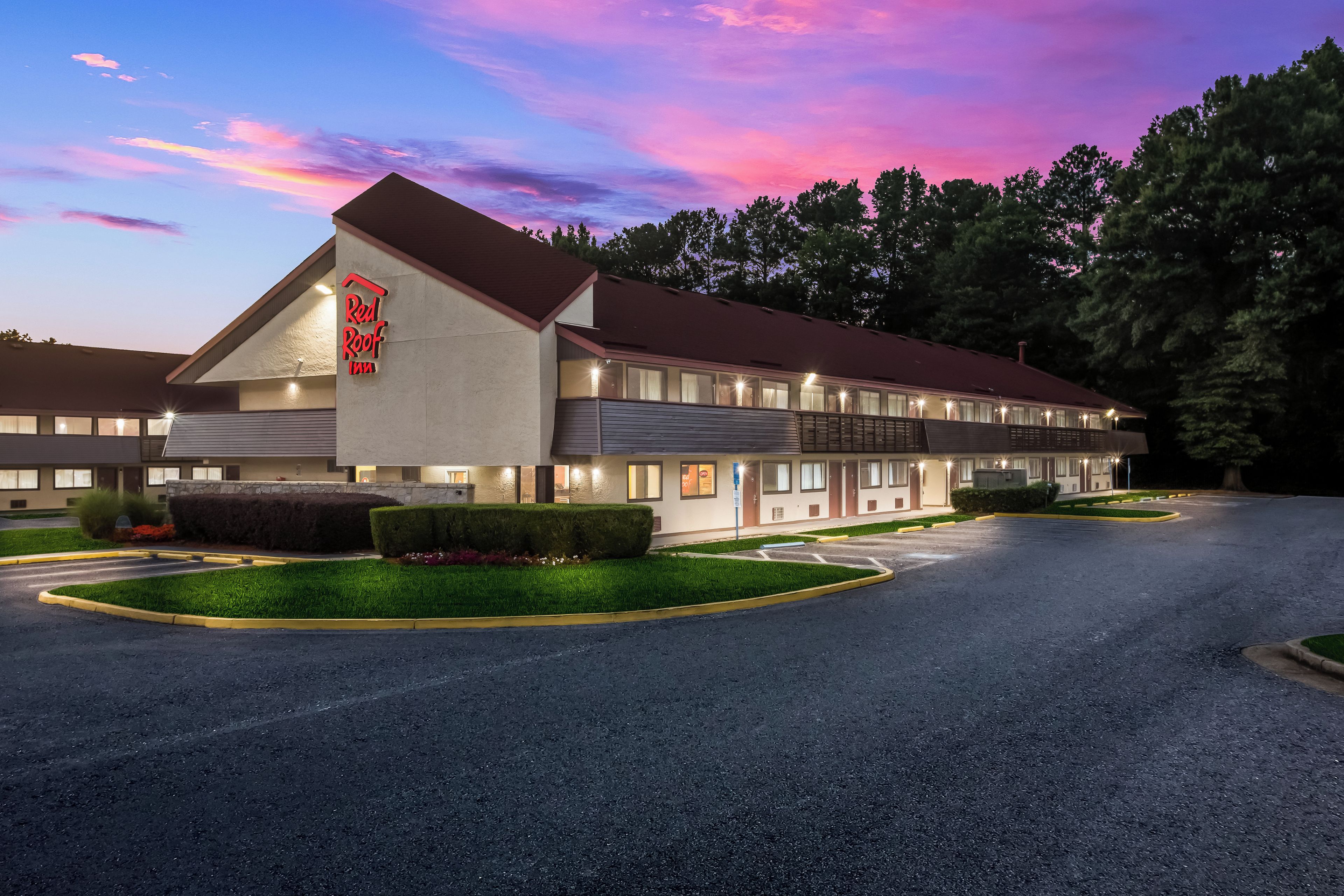 A Red Roof Inn with a two-story structure, a parking lot, and a well-maintained lawn.