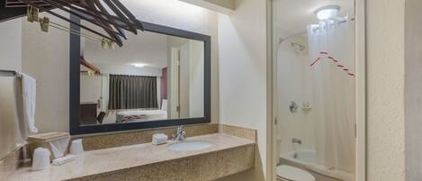 Un baño con lavamanos, espejo, inodoro y ducha.