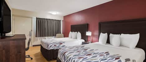 Une chambre d’hôtel avec deux lits, un bureau, une chaise et un téléviseur.