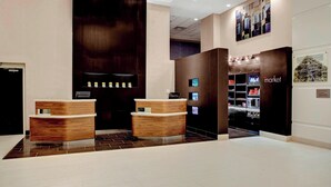 A modern reception area with wooden reception desks, a digital display, and a 'market' sign. - Courtyard by Marriott Columbus Downtown (Columbus)