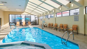 An indoor swimming pool with clear water, lounge chairs, and a sunroof. - Courtyard by Marriott Columbus Downtown (Columbus)