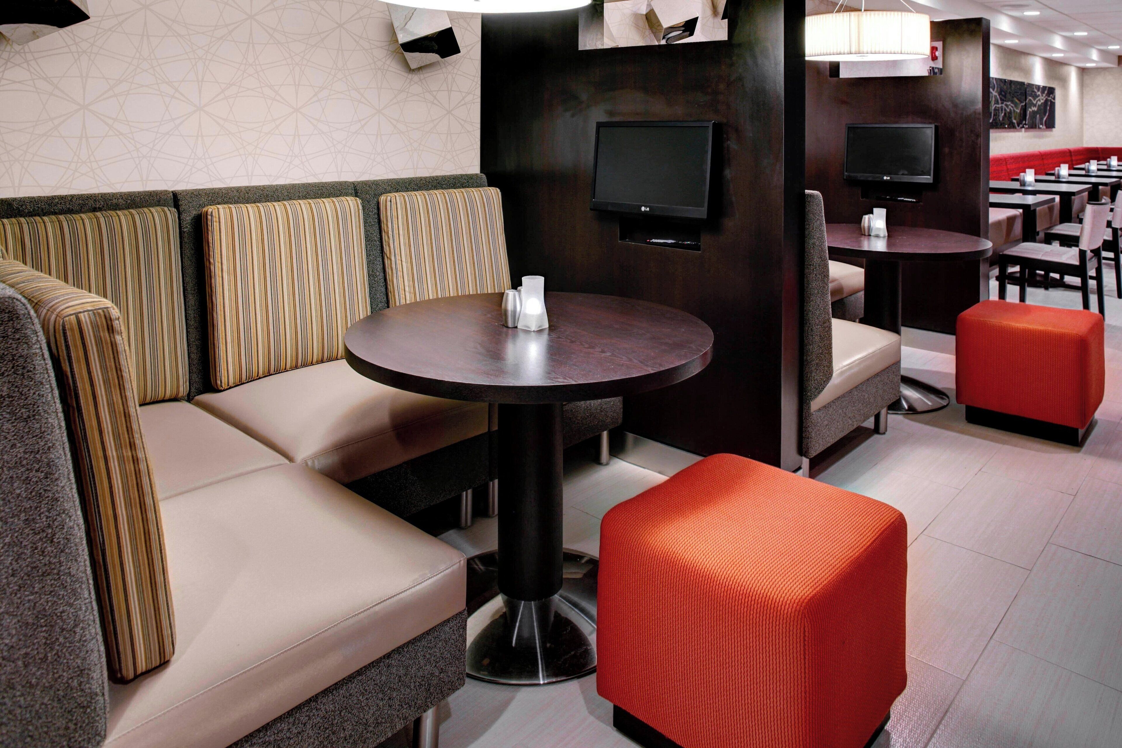 L’intérieur d’un restaurant moderne est agrémenté de sièges rembourrés, d’une table ronde et d’un téléviseur à écran plat fixé au mur.