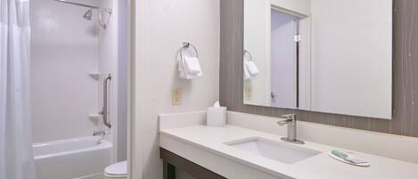 A modern bathroom with a bathtub, toilet, sink, and a large mirror.