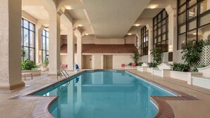 An indoor swimming pool with a tiled deck, large windows, and potted plants. - Embassy Suites Hotel Baton Rouge (Baton Rouge)