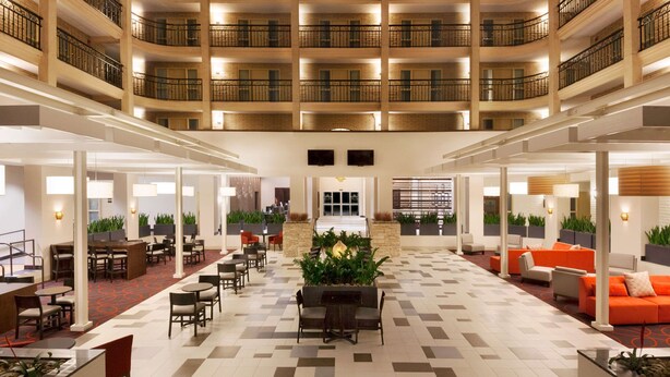 A multi-level hotel lobby with a central seating area, multiple floors with balconies, and a check-in counter. - Embassy Suites Hotel Baton Rouge (Baton Rouge)