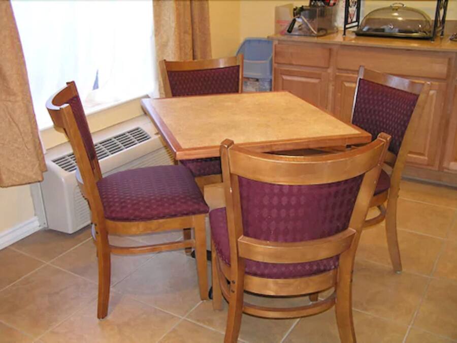A dining area with a wooden table and four chairs with purple cushions.