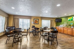 Guests can enjoy meals in this dining area with multiple tables and chairs, a counter offering a self-service breakfast option, and a flat-screen TV.