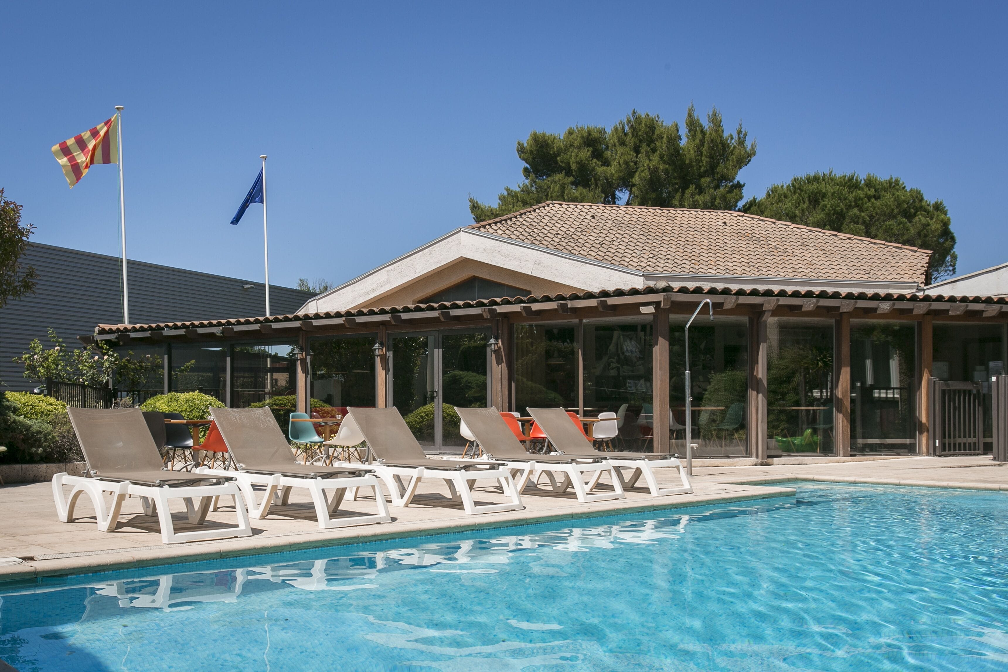 Une piscine avec des chaises longues et un espace salon abrité.