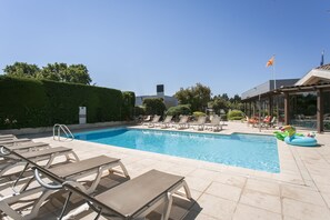 Una piscina al aire libre, sombrillas, sillones reclinables de piscina