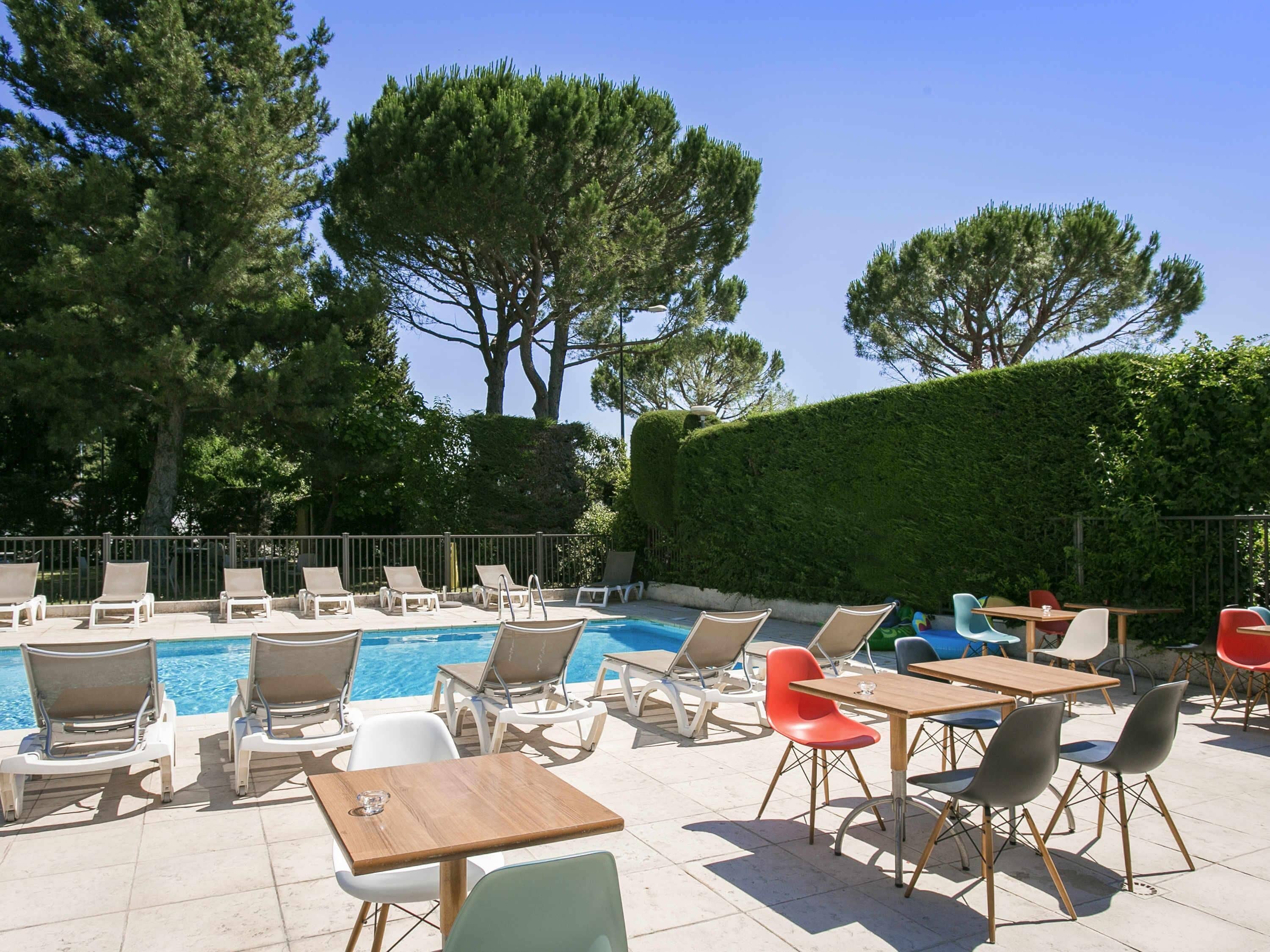 Una piscina al aire libre, sombrillas, sillones reclinables de piscina