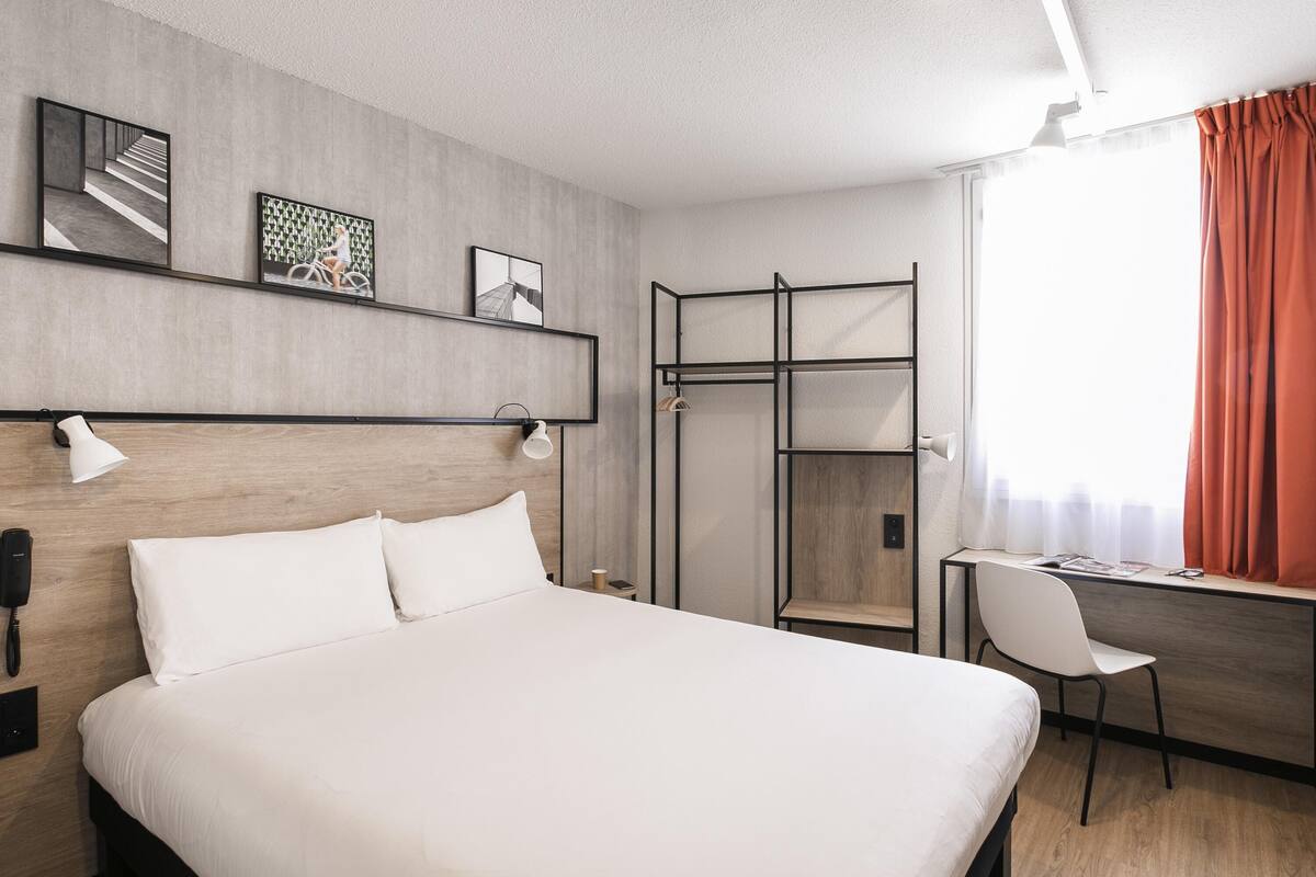 A hotel room with a bed, desk, chair, and a walk-in closet.