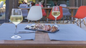 An outdoor dining area with a table set for two, featuring a glass of white wine and a plate of cured meats. - ibis Avignon Sud (Avignon)