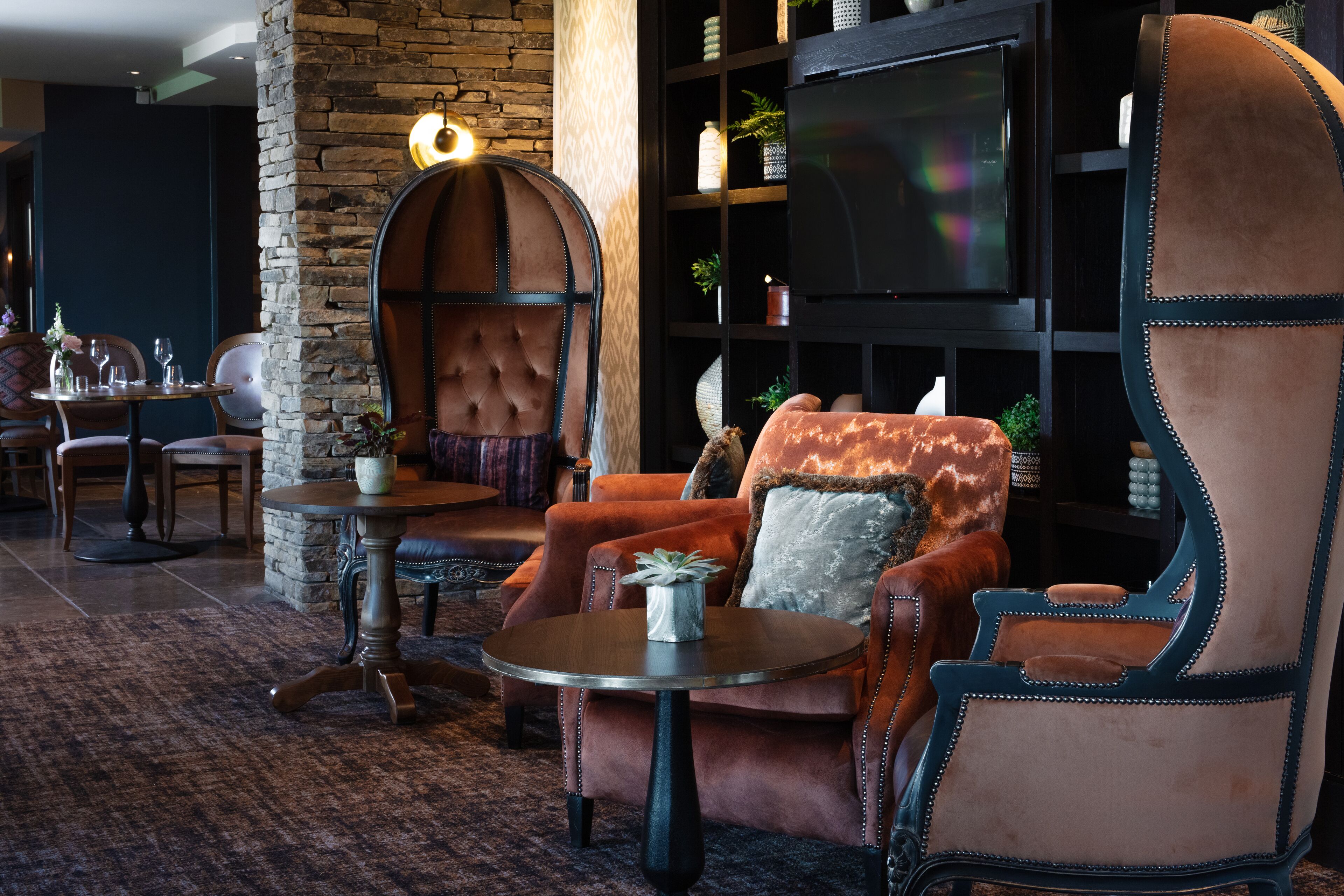 A cozy lounge area with leather armchairs, a round table, and a television.