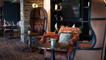 A cozy lounge area with leather armchairs, a round table, and a television.
