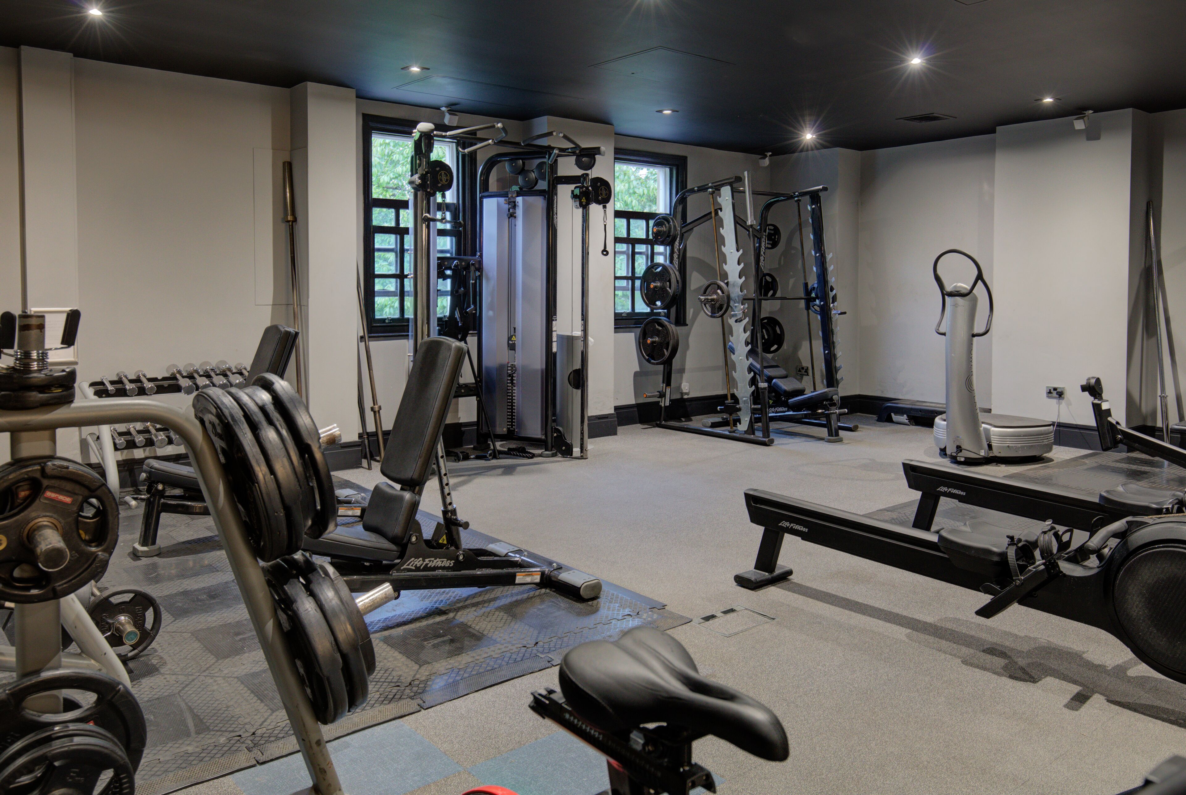 A gym with various exercise equipment, including dumbbells, a bench press, and a treadmill.