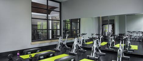 A gym with stationary bikes, weights, and exercise mats.