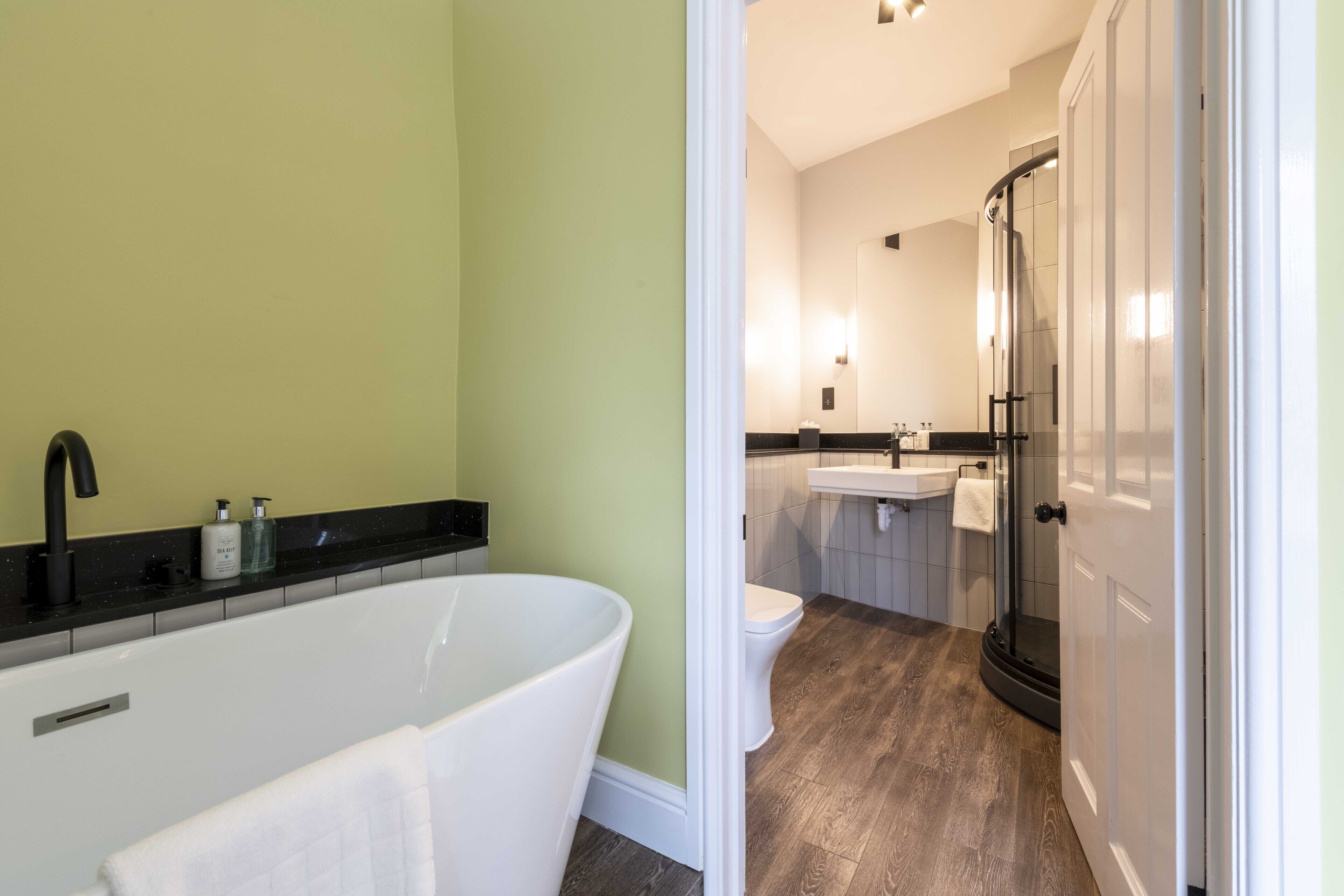 A modern bathroom with a freestanding bathtub, a glass shower enclosure, and a white sink.