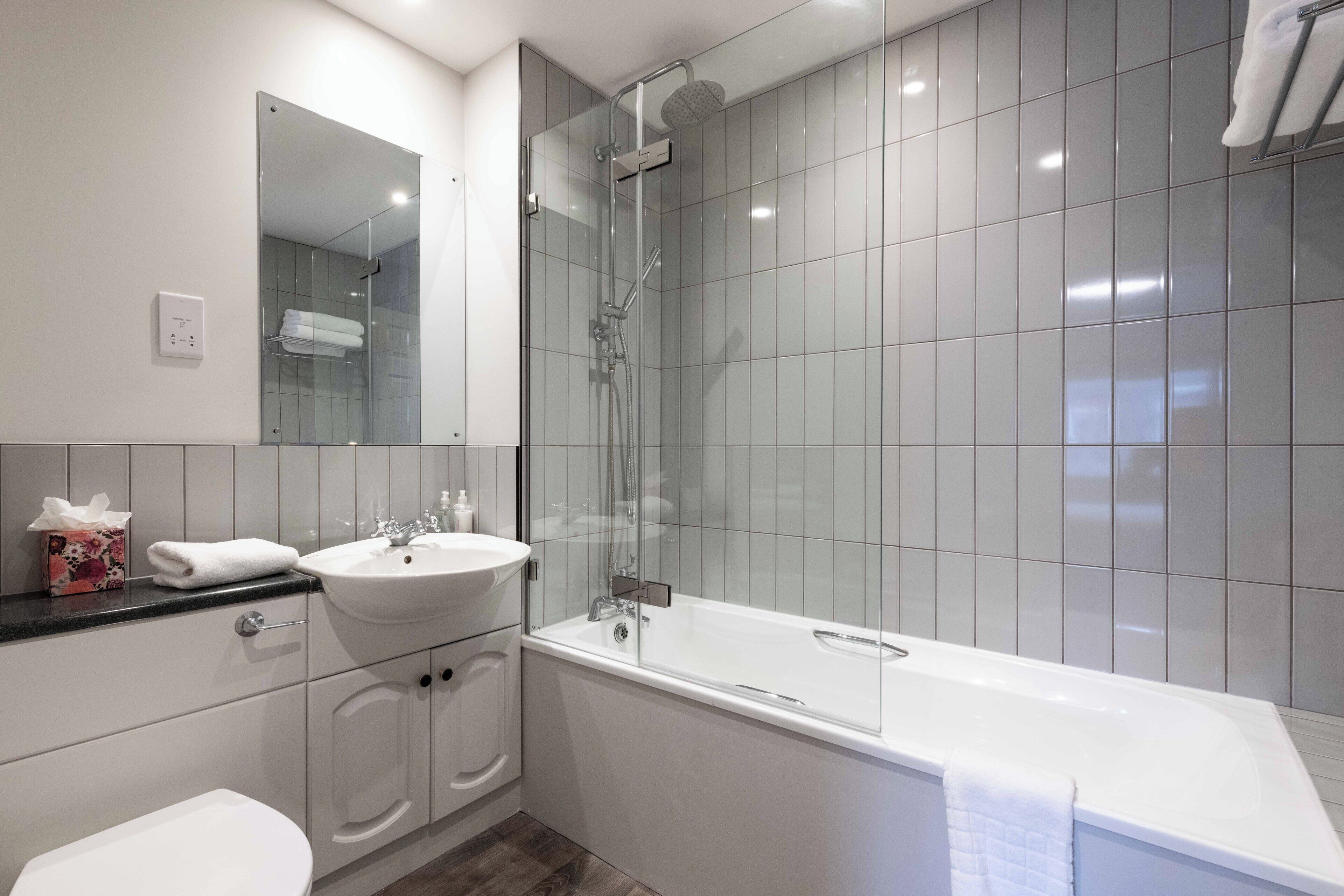 A modern bathroom with a glass-enclosed shower, a white sink, and a bathtub.