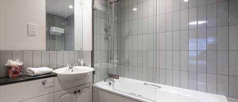 A modern bathroom with a glass-enclosed shower, a white sink, and a bathtub.