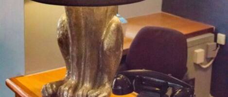 A lamp with a rabbit design on a wooden table, a rotary phone, and a blue wall in the background.