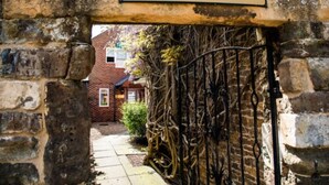 A stone archway with a sign reading "HOTEL RECEPTION" leading to a building with a brick facade and a window. - The Wisteria Hotel (Oakham)