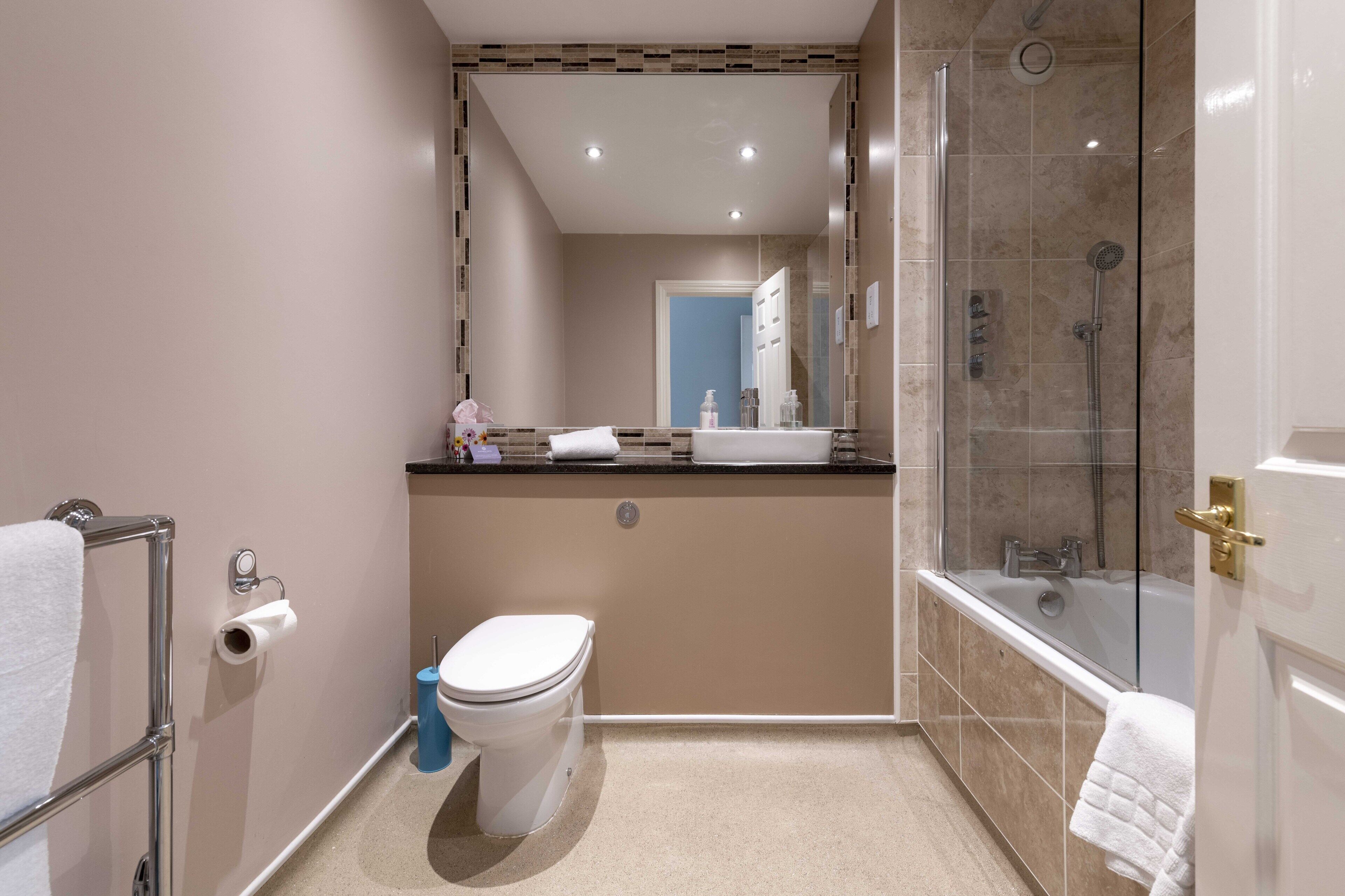 A modern bathroom with a toilet, sink, and shower.