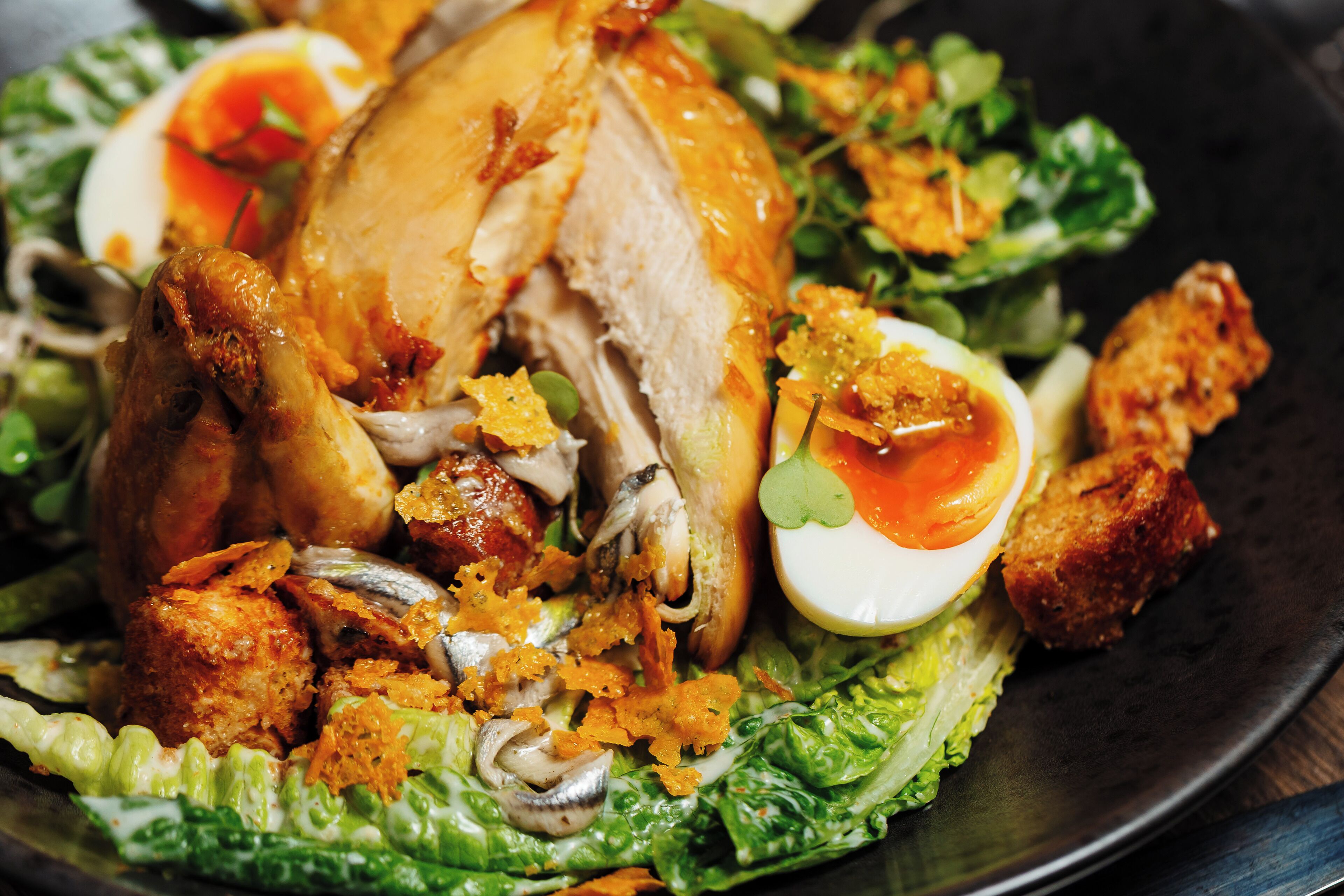 A roasted chicken with vegetables and a side salad on a plate.