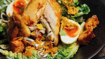 A roasted chicken with vegetables and a side salad on a plate.