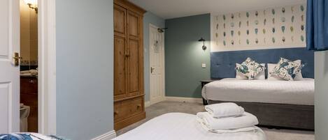 Un dormitorio con dos camas, un armario, un baño y una lámpara de techo.