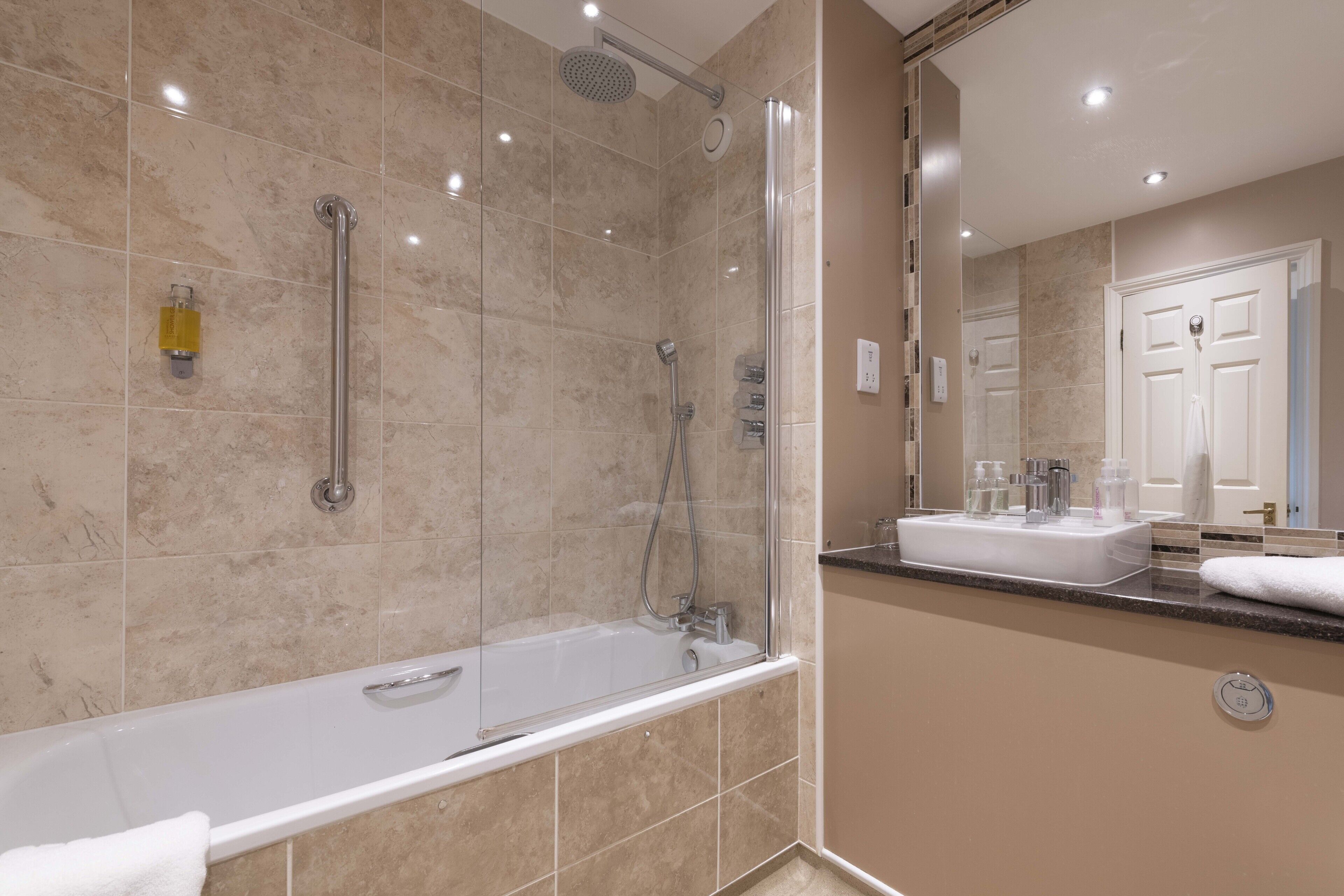 A modern bathroom with a glass-enclosed shower, a standalone bathtub, and a vanity with a mirror.