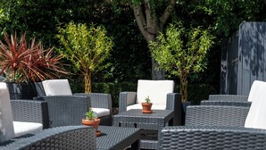 An outdoor seating area with wicker furniture and potted plants. - The Wisteria Hotel (Oakham)