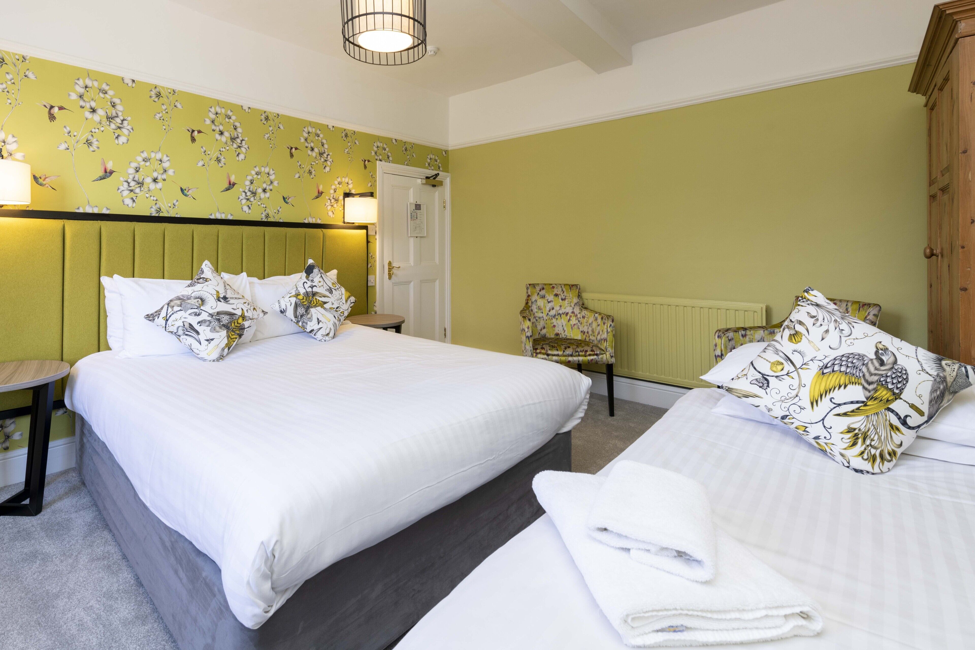 A hotel room with a large bed, a chair, and a radiator.