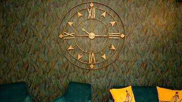 Une horloge murale avec des chiffres romains et un motif décoratif représentant des plumes.