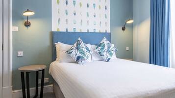 A bedroom with a bed, two wall-mounted lamps, a small round table, and a patterned wall.