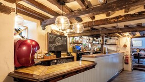 A bar area with a wooden counter, a red suitcase, and a chalkboard menu. - The Wisteria Hotel (Oakham)