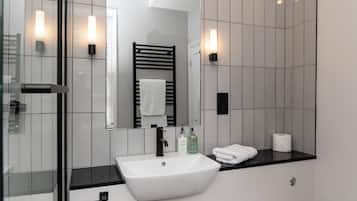 A modern bathroom with a white sink, black faucet, and a glass shower enclosure.