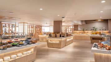 Un área de desayuno moderna con mostradores de madera, diversos alimentos y un interior limpio y bien iluminado.