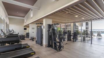 Un gimnasio moderno con cintas de correr, máquinas de pesas y un amplio ventanal con vistas al exterior.